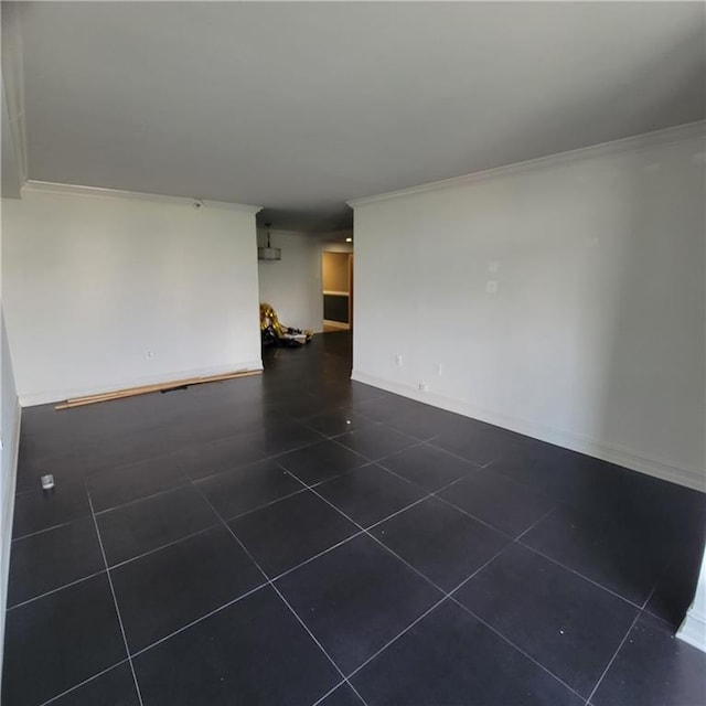 unfurnished living room featuring dark tile patterned floors, baseboards, and ornamental molding