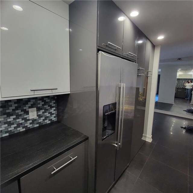 kitchen featuring decorative backsplash, high end refrigerator, and dark tile patterned floors