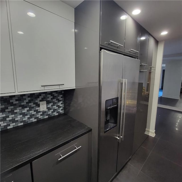 kitchen featuring dark tile patterned flooring, high quality fridge, and tasteful backsplash