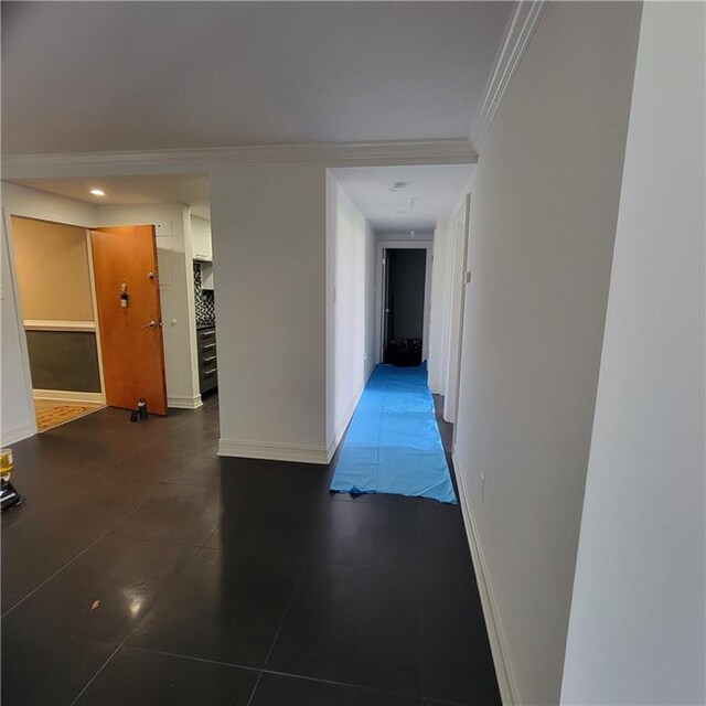 hall featuring ornamental molding and dark tile patterned flooring