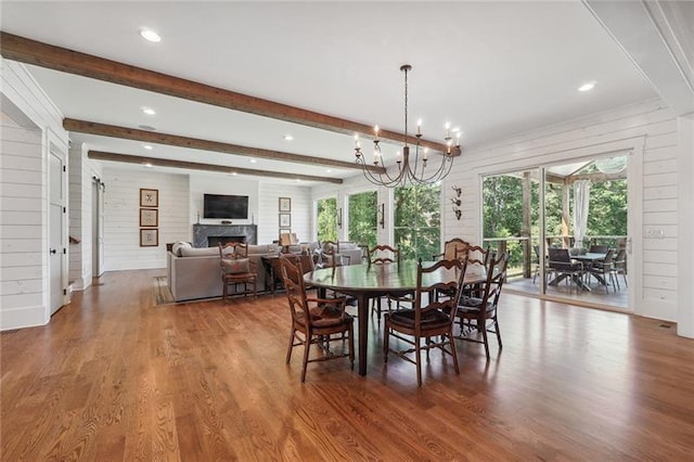 dining room featuring beamed ceiling, hardwood / wood-style floors, a chandelier, and wood walls