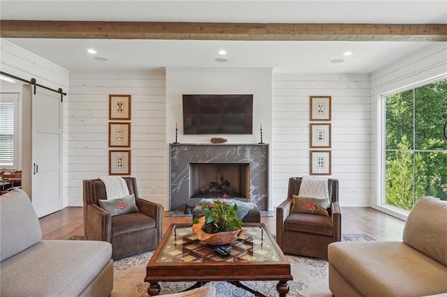 living room featuring hardwood / wood-style flooring, a fireplace, a barn door, and wood walls