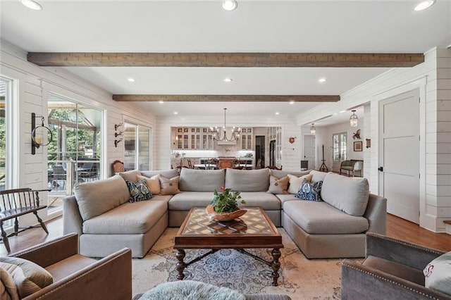 living room featuring beam ceiling, an inviting chandelier, and light hardwood / wood-style floors