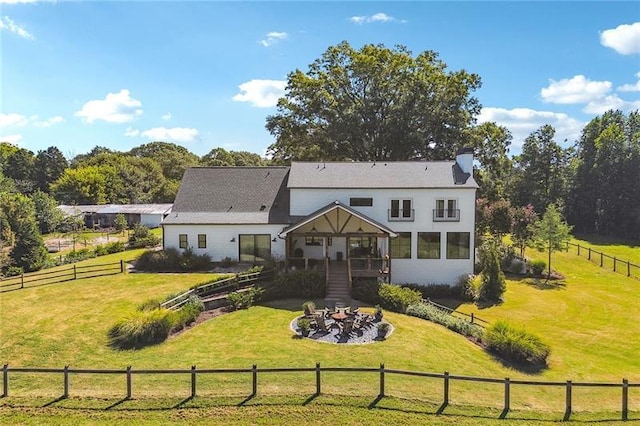 back of house with a rural view and a yard