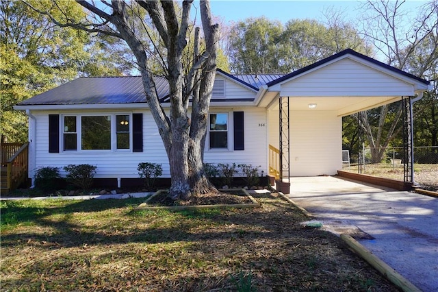 ranch-style house featuring a carport, concrete driveway, metal roof, and fence