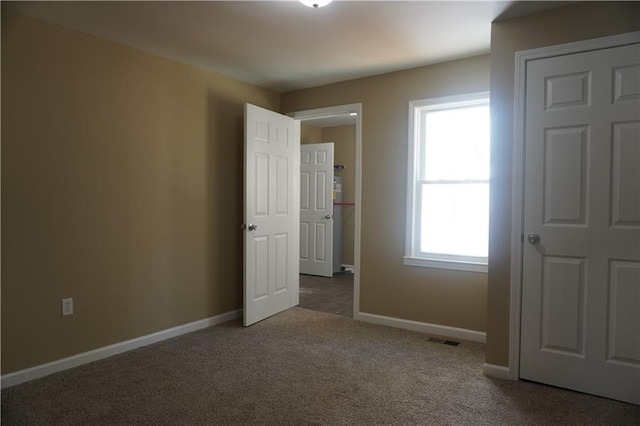 unfurnished bedroom with carpet floors, visible vents, and baseboards