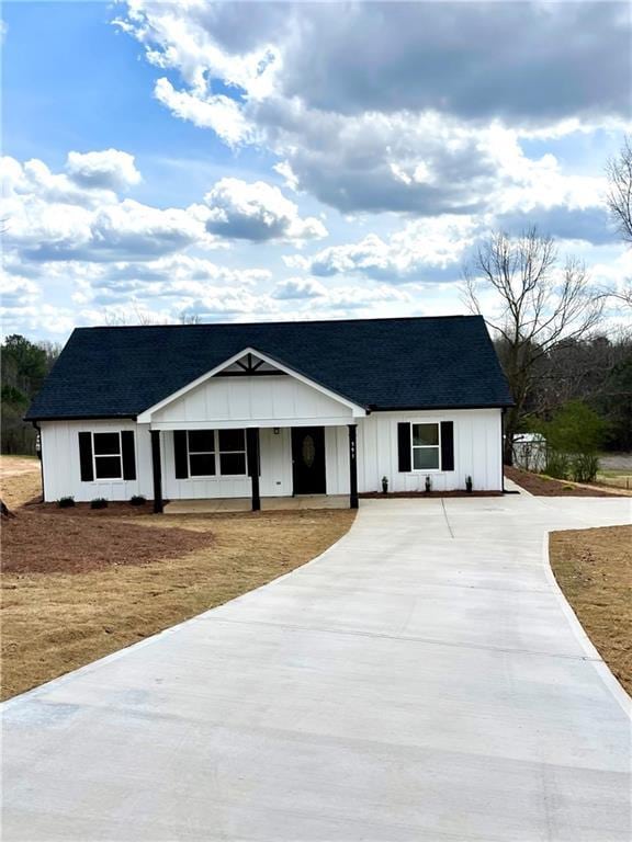 modern farmhouse with driveway, roof with shingles, and board and batten siding