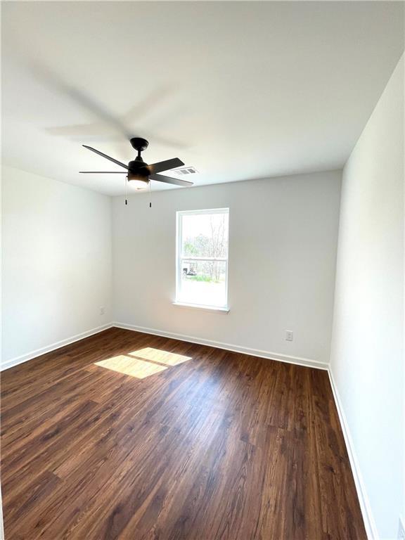 unfurnished room with baseboards, dark wood-style flooring, and ceiling fan