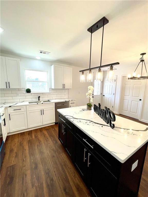 kitchen featuring visible vents, a center island, decorative backsplash, white cabinets, and stainless steel dishwasher