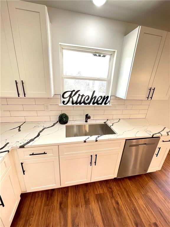 kitchen featuring dishwasher, dark wood finished floors, light stone countertops, and a sink