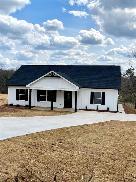 modern farmhouse featuring a front lawn, concrete driveway, board and batten siding, and a shingled roof