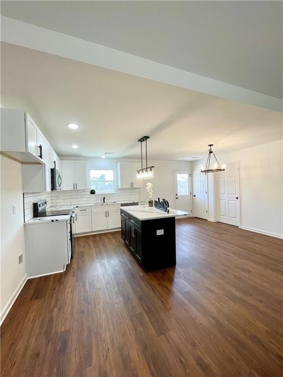 kitchen featuring stainless steel microwave, a healthy amount of sunlight, light countertops, and electric range oven