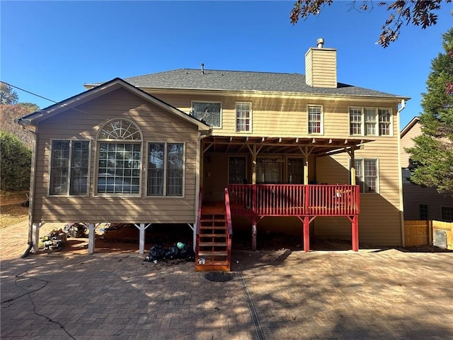 back of property with roof with shingles, a chimney, and a wooden deck