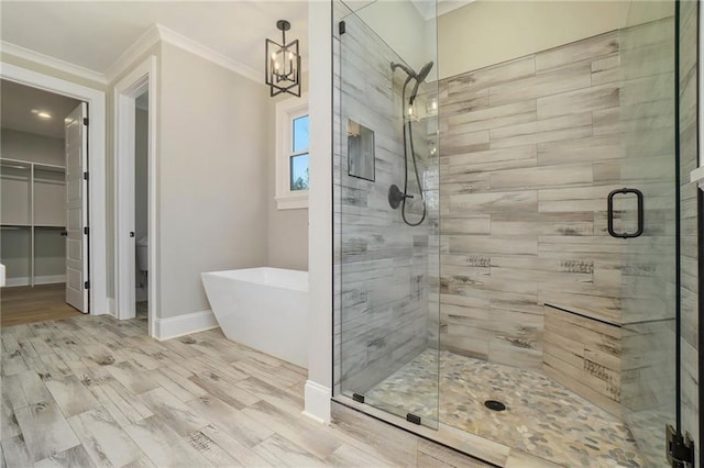 full bath with a shower stall, ornamental molding, a soaking tub, baseboards, and a chandelier