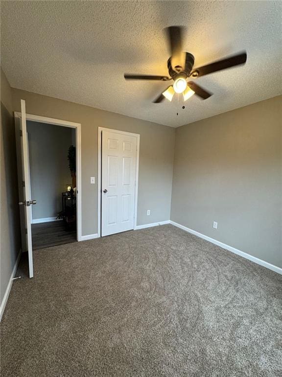 unfurnished bedroom featuring a textured ceiling, dark carpet, and ceiling fan