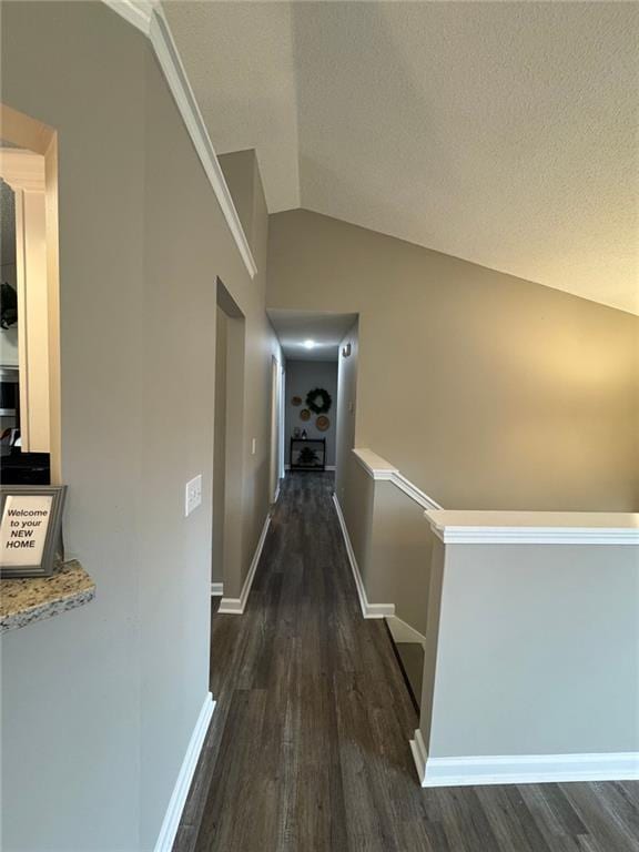 hallway with dark hardwood / wood-style floors, lofted ceiling, and a textured ceiling