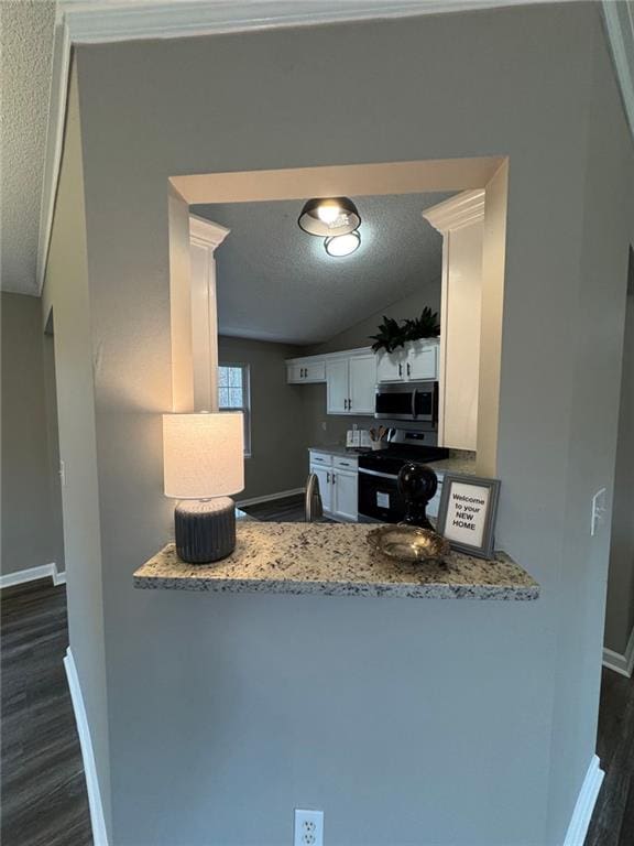 kitchen featuring light stone countertops, a textured ceiling, electric range, white cabinetry, and lofted ceiling