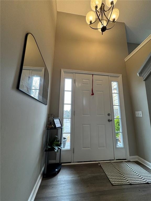 foyer with a towering ceiling, dark hardwood / wood-style flooring, an inviting chandelier, and a healthy amount of sunlight