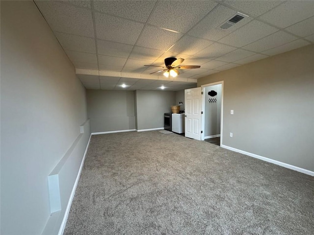 interior space with ceiling fan, a drop ceiling, and dark carpet