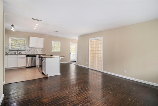 kitchen featuring dark hardwood / wood-style flooring, white cabinetry, stainless steel dishwasher, and a healthy amount of sunlight