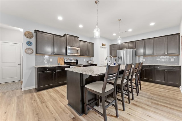 6021 Harbour Mist Dr, Flowery Branch, GA 30542 - kitchen featuring appliances with stainless steel finishes, dark brown cabinetry, decorative backsplash, light wood-type flooring, and recessed lighting