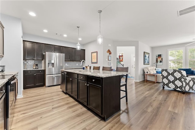 6021 Harbour Mist Dr, Flowery Branch, GA 30542 - kitchen featuring stainless steel appliances, open floor plan, a kitchen breakfast bar, light wood finished floors, and decorative backsplash