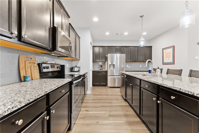 6021 Harbour Mist Dr, Flowery Branch, GA 30542 - kitchen with appliances with stainless steel finishes, pendant lighting, light wood-style flooring, tasteful backsplash, and recessed lighting