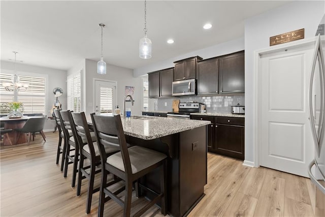 6021 Harbour Mist Dr, Flowery Branch, GA 30542 - kitchen featuring appliances with stainless steel finishes, a breakfast bar area, light wood-type flooring, backsplash, and healthy amount of natural light