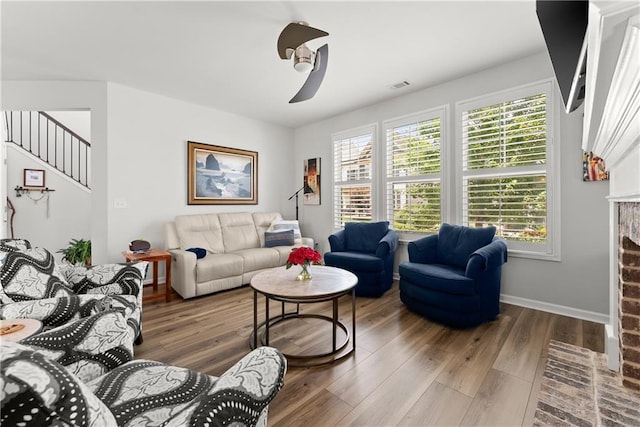 6021 Harbour Mist Dr, Flowery Branch, GA 30542 - living room featuring a fireplace with flush hearth, wood finished floors, stairway, and ceiling fan