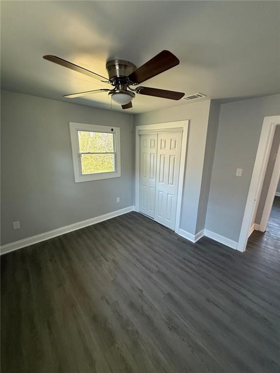 unfurnished bedroom featuring visible vents, a ceiling fan, dark wood-style floors, a closet, and baseboards