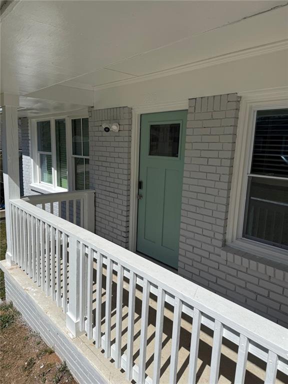 view of exterior entry with brick siding and covered porch