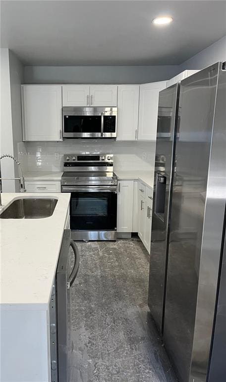 kitchen with a sink, stainless steel appliances, white cabinetry, and light countertops