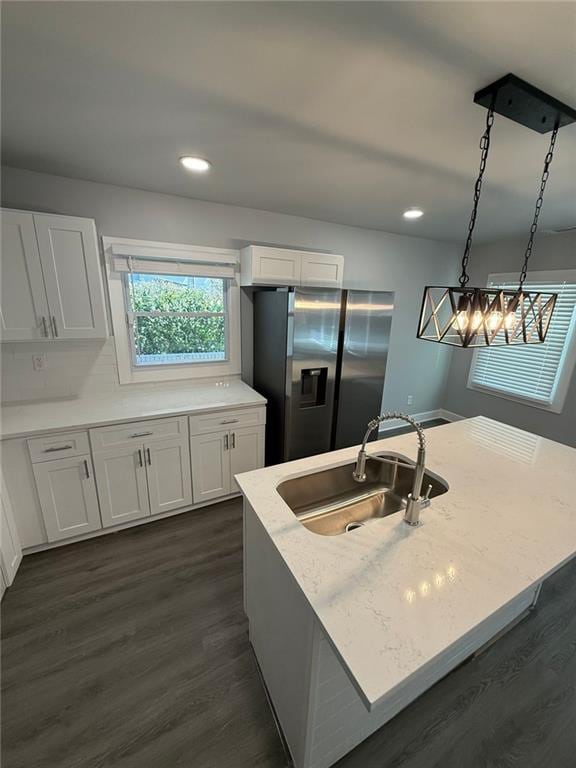 kitchen featuring light stone countertops, dark wood finished floors, stainless steel refrigerator with ice dispenser, white cabinetry, and a sink