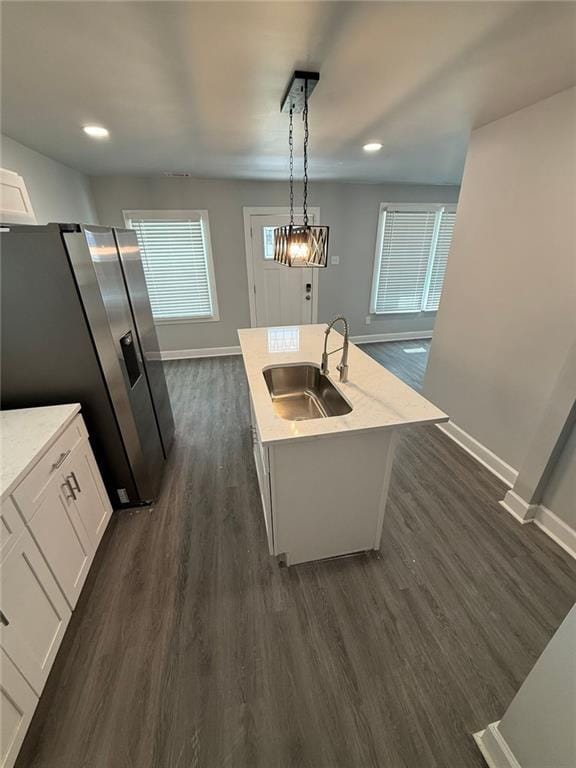 kitchen with a sink, dark wood finished floors, white cabinetry, stainless steel fridge, and baseboards