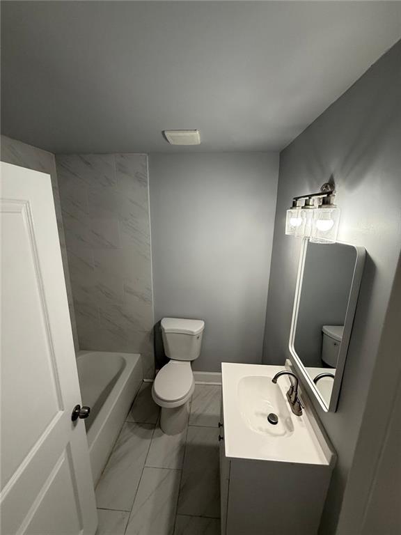 bathroom with vanity, toilet, baseboards, and marble finish floor