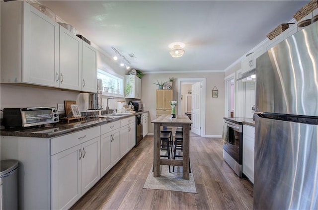 214 Iron St NW, Rome, GA 30165 - kitchen with stainless steel appliances, under cabinet range hood, a sink, dark wood-type flooring, and ornamental molding