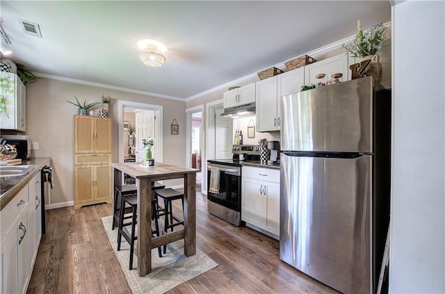 214 Iron St NW, Rome, GA 30165 - kitchen featuring appliances with stainless steel finishes, under cabinet range hood, dark countertops, white cabinets, and crown molding