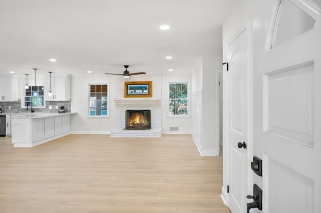 living room with ceiling fan, light wood-style flooring, recessed lighting, baseboards, and a brick fireplace