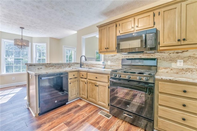 kitchen with a textured ceiling, light wood-type flooring, plenty of natural light, and black appliances