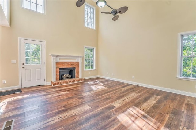 unfurnished living room featuring wood-type flooring, a towering ceiling, and a wealth of natural light