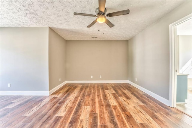 empty room with ceiling fan, wood-type flooring, and a textured ceiling