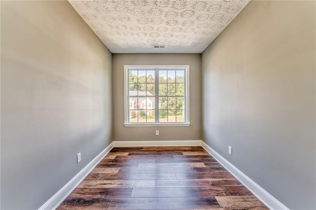 spare room with dark hardwood / wood-style floors and a textured ceiling