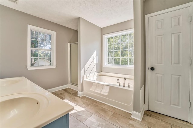 bathroom featuring vanity, separate shower and tub, and a textured ceiling