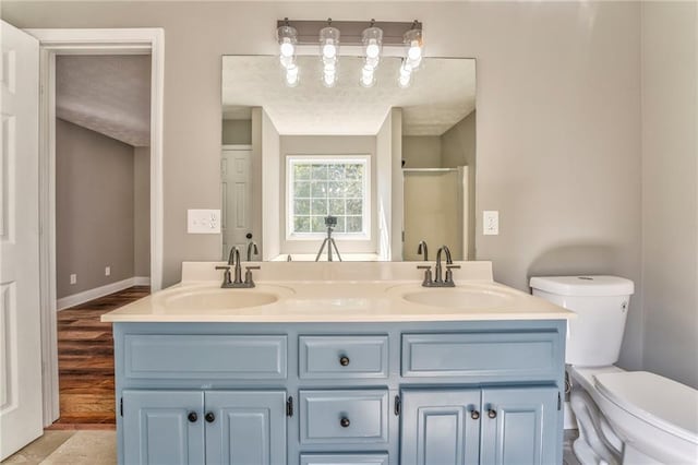 bathroom featuring a shower with door, hardwood / wood-style flooring, vanity, and toilet