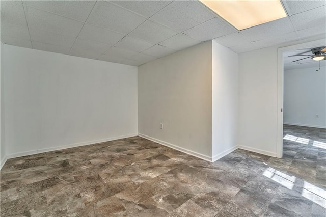 basement featuring ceiling fan and a paneled ceiling