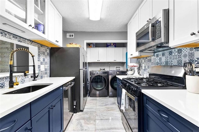 kitchen featuring sink, washing machine and dryer, blue cabinetry, and appliances with stainless steel finishes