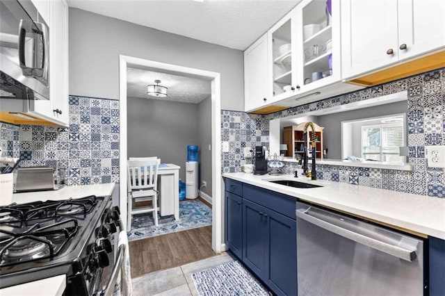 kitchen with sink, light tile patterned floors, a textured ceiling, appliances with stainless steel finishes, and white cabinetry