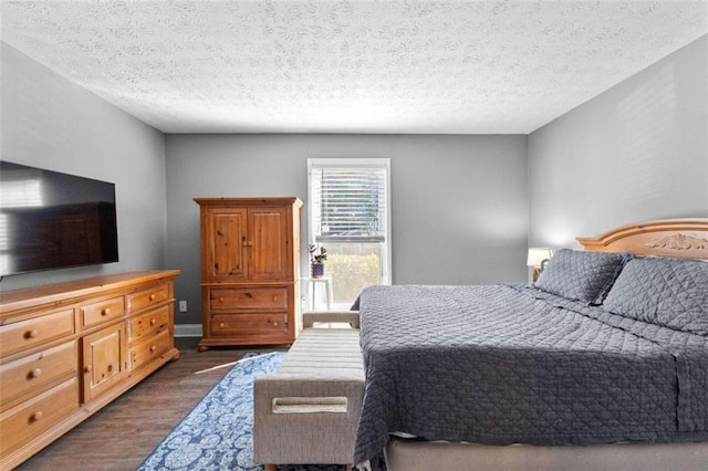 bedroom with dark hardwood / wood-style floors and a textured ceiling