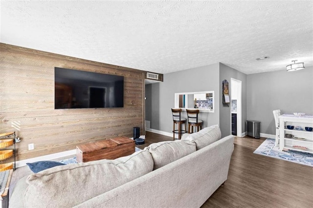 living room with wood walls, dark wood-type flooring, and a textured ceiling