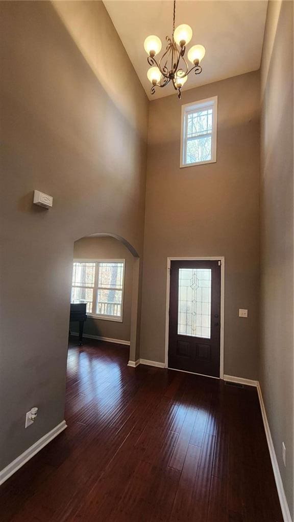 entryway featuring dark hardwood / wood-style floors, a chandelier, and a towering ceiling